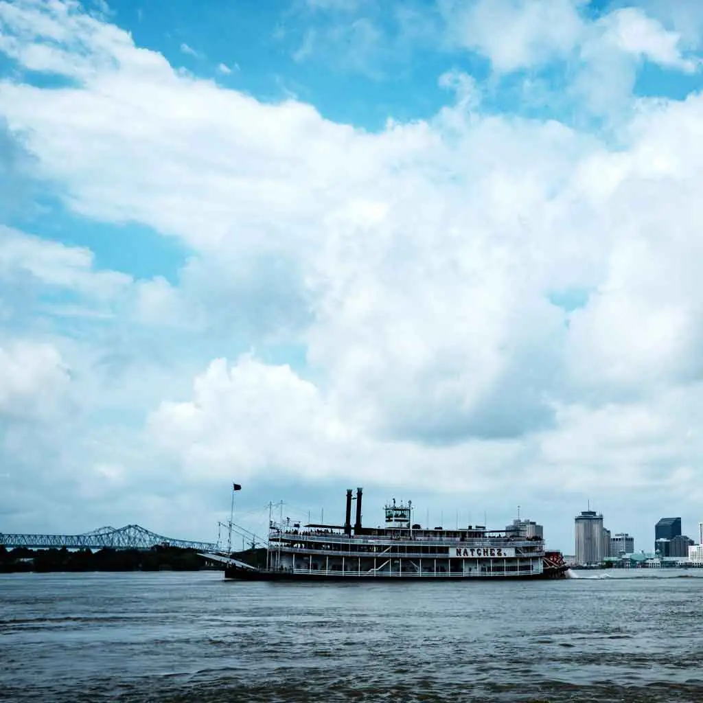 Photograph of blue, yet cloudy, skies with a steamboat floating by with a sign that says "Natchez."