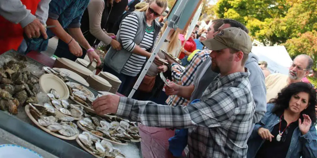 Crowds surrounding a table full of wellfleet oysters at the Wellfleet OysterFest.