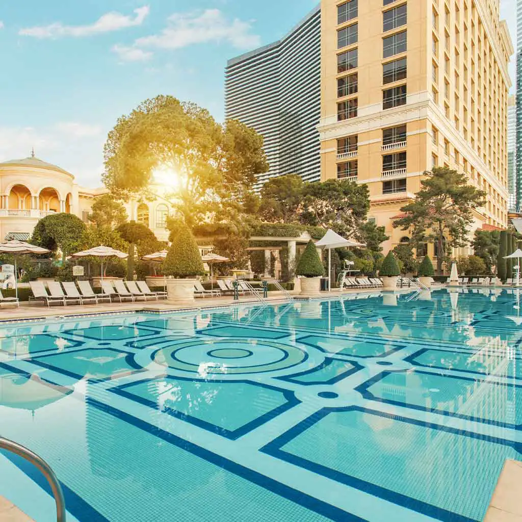 Landscape view of a large, empty resort pool with a hotel in the background.