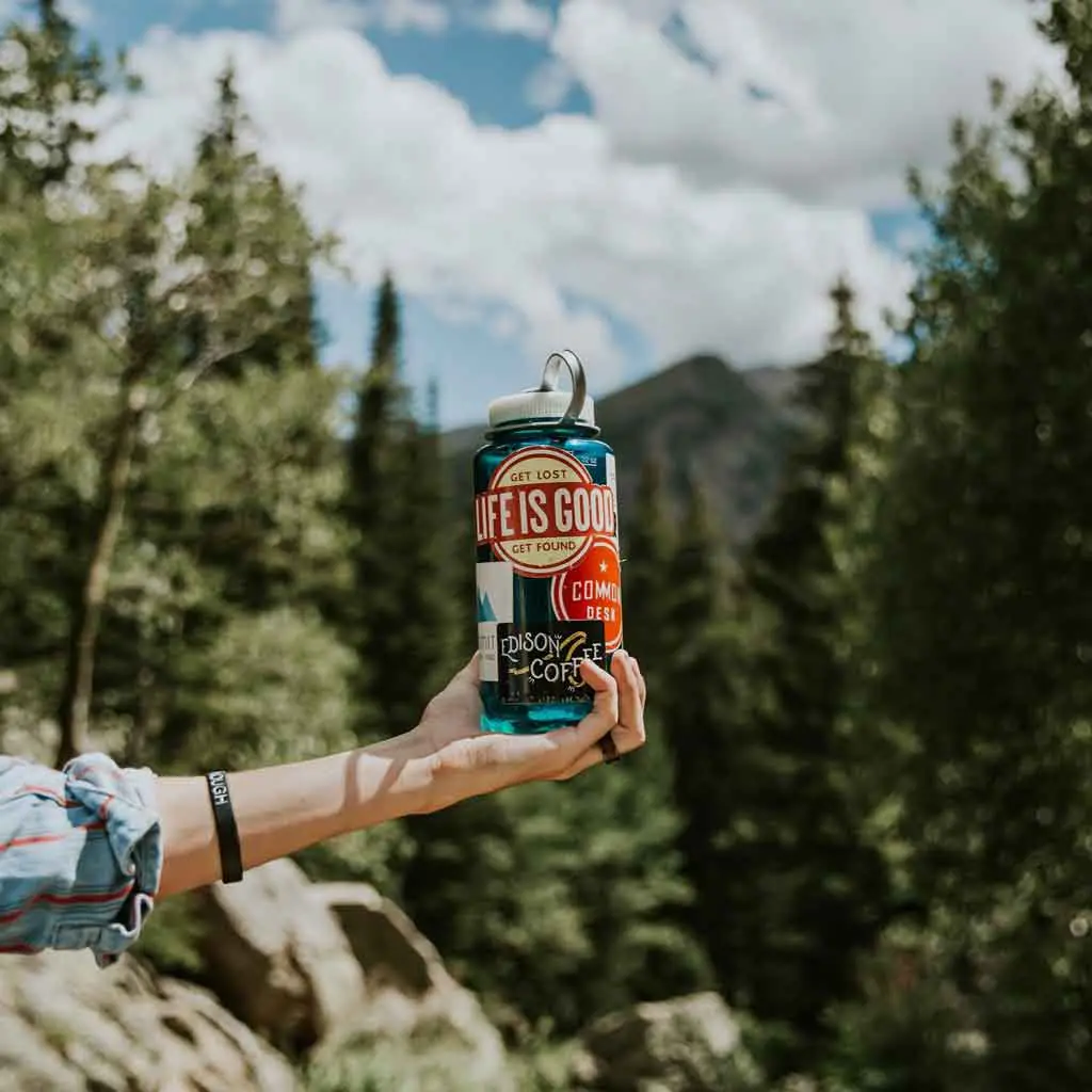 Photo of a person holding up a reusable water bottle with stickers on it