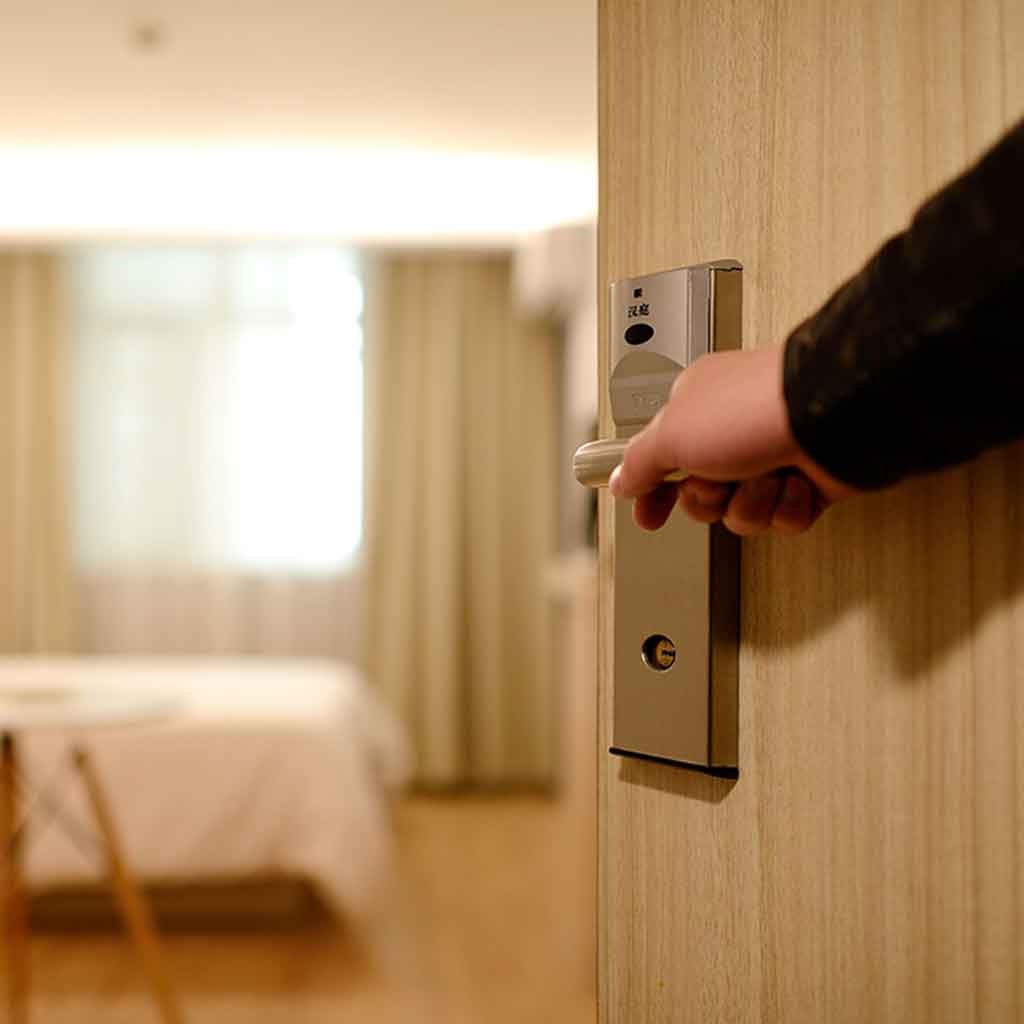 Closeup of a person opening a door to a hotel room.