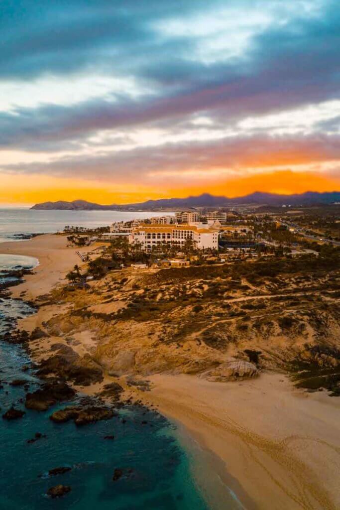 Aerial view of a large building set up on a hill, overlooking the ocean.