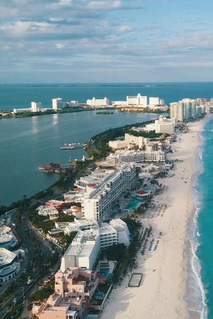 Aerial view of a long stretch of beach with many tall and large buildings down the coast.