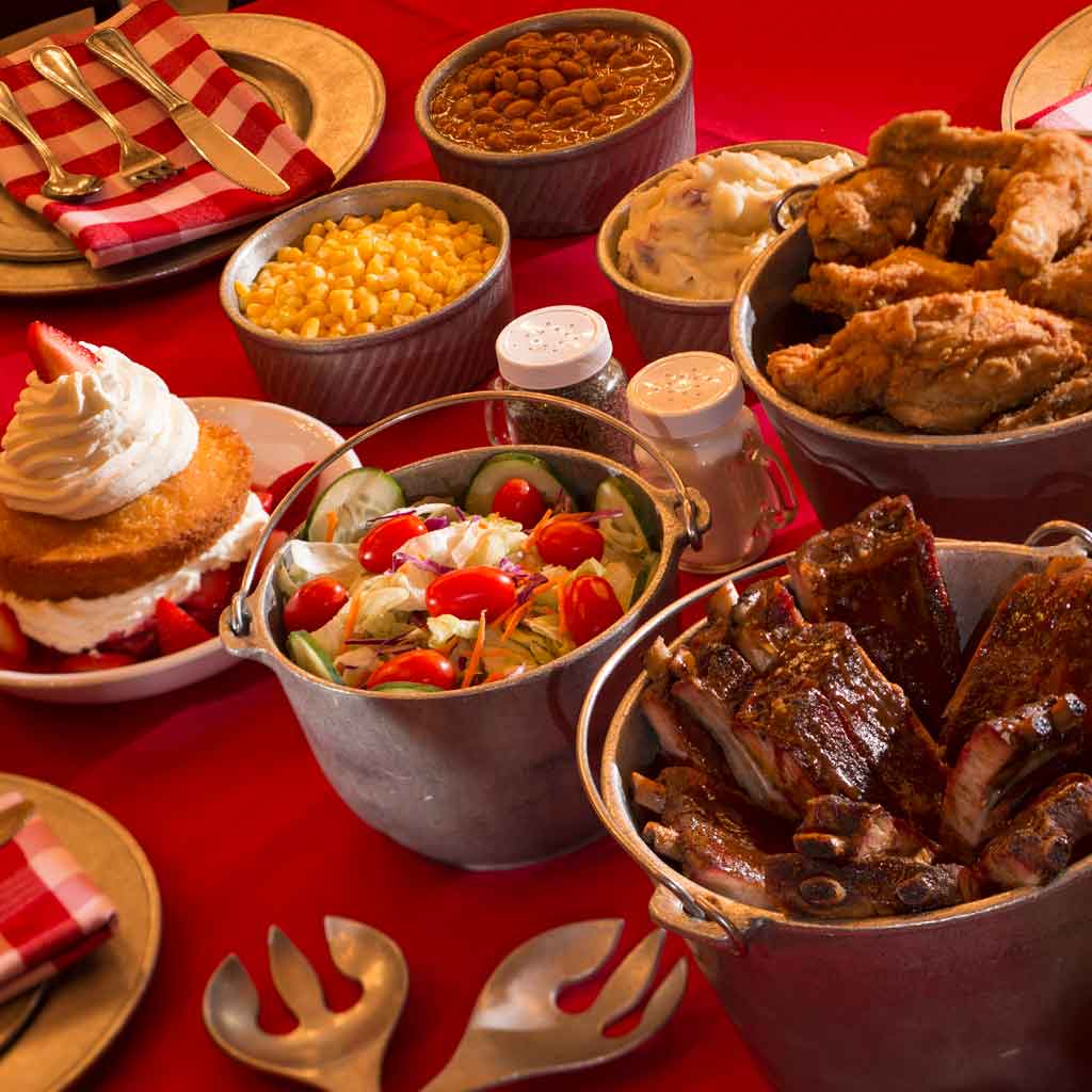 Closeup photo of a table with buckets and bowls full of barbecue foods.