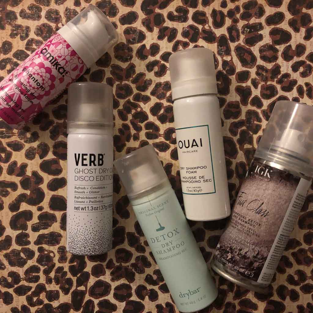 Photo of 5 trial sized cans of dry shampoo artfully arranged on top of a leopard print surface.