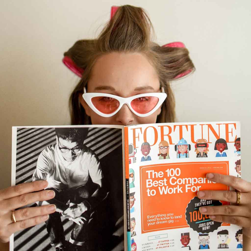 Photo of a woman with velcro rollers in her hair holding up a Fortune magazine in front of her.