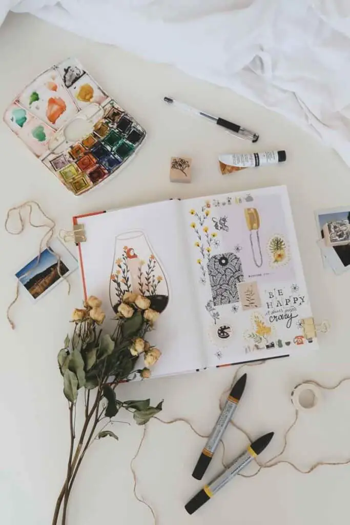 Flat lay photo of a scrapbook surrounded by craft and art supplies.