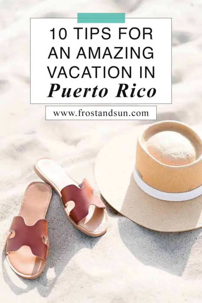 Flat lay photo of a pair of brown flat sandals next to a straw hat on a sandy beach. Overlying text reads "10 Tips for An Amazing Vacation in Puerto Rico."