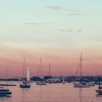 Photo of the Boston skyline during sunset with boats in the water.
