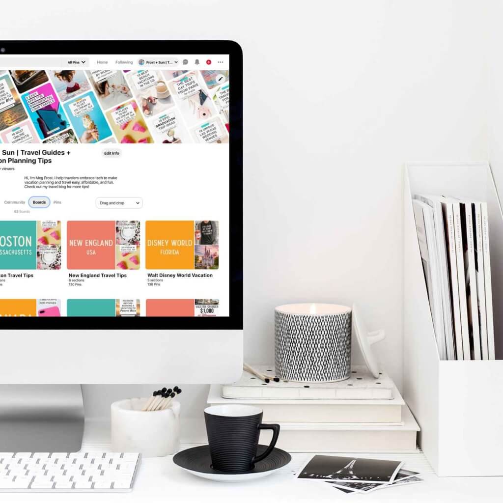 Closeup photo of a desk with magazines, a candle, and a coffee cup to the right of a Macintosh computer opened on a Pinterest profile page.