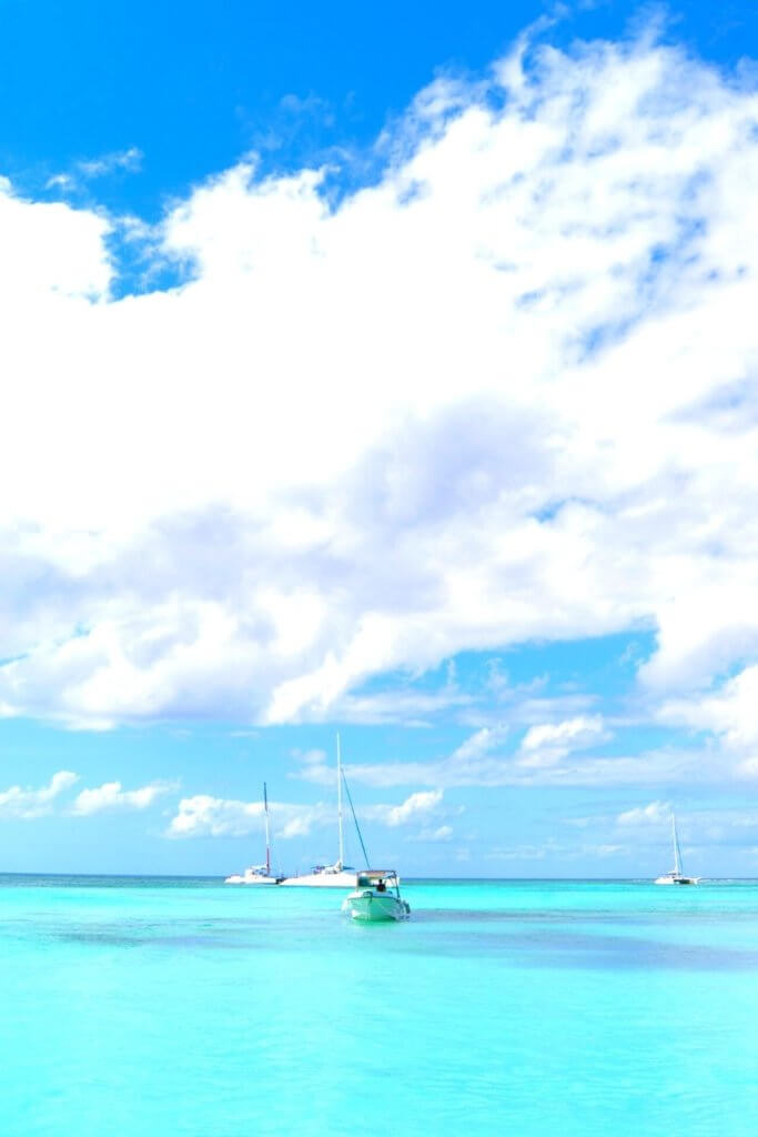 Photo of boats floating in the ocean in turquoise Caribbean waters.
