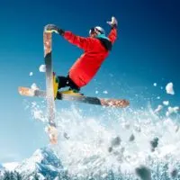 Photo of a person in colorful snow gear on skis mid-air off a ski jump.