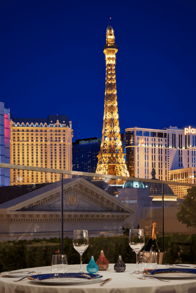 Photo of a table set for 2 on the rooftop of Paris Las Vegas with views of the Eiffel Tower replica.