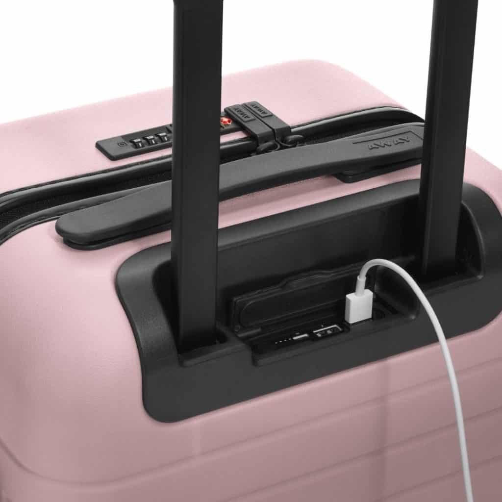 Closeup of a pink hardshell suitcase with a built-in power bank.