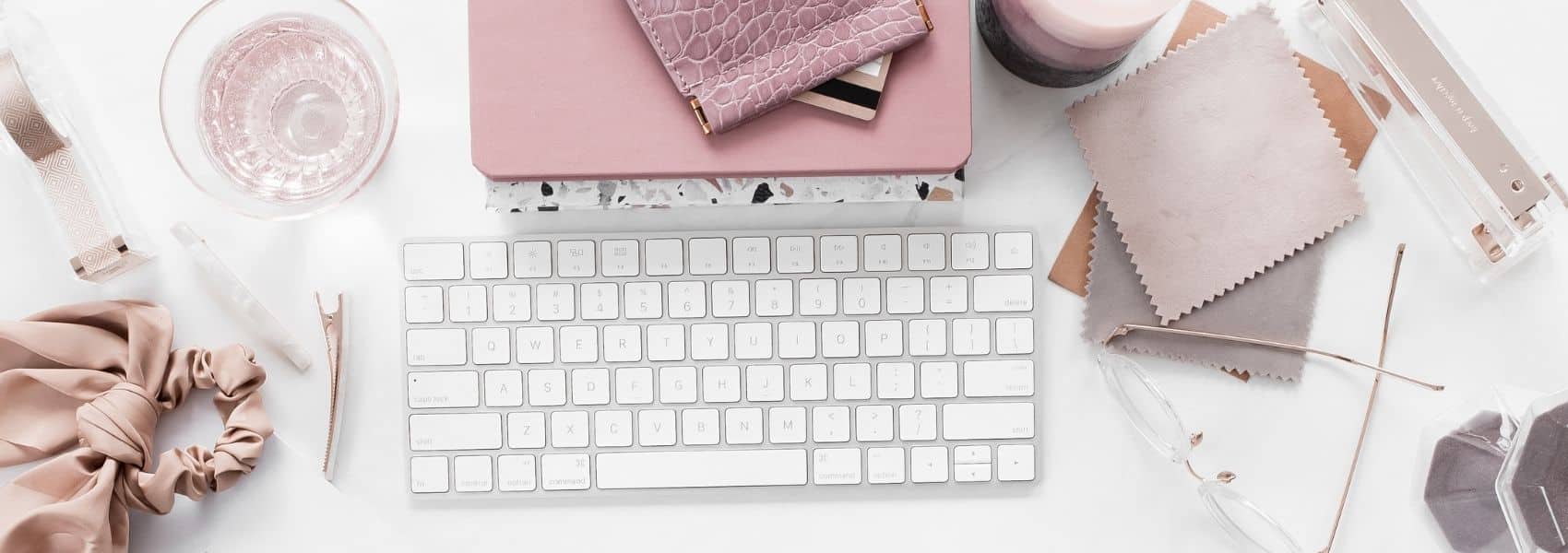 Flatlay photo of a keyboard and other office supplies artfully arranged on a desk.