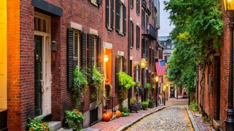 Landscape view of a cobblestone alley with brick townhomes in Beacon Hill, Boston.