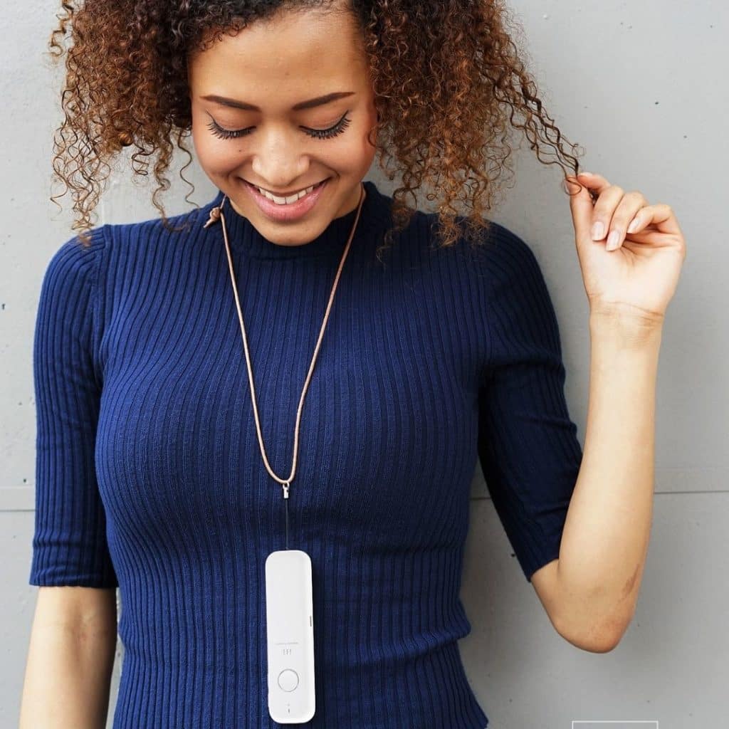 Closeup of a young woman wearing an ili language translator around her neck like a necklace.