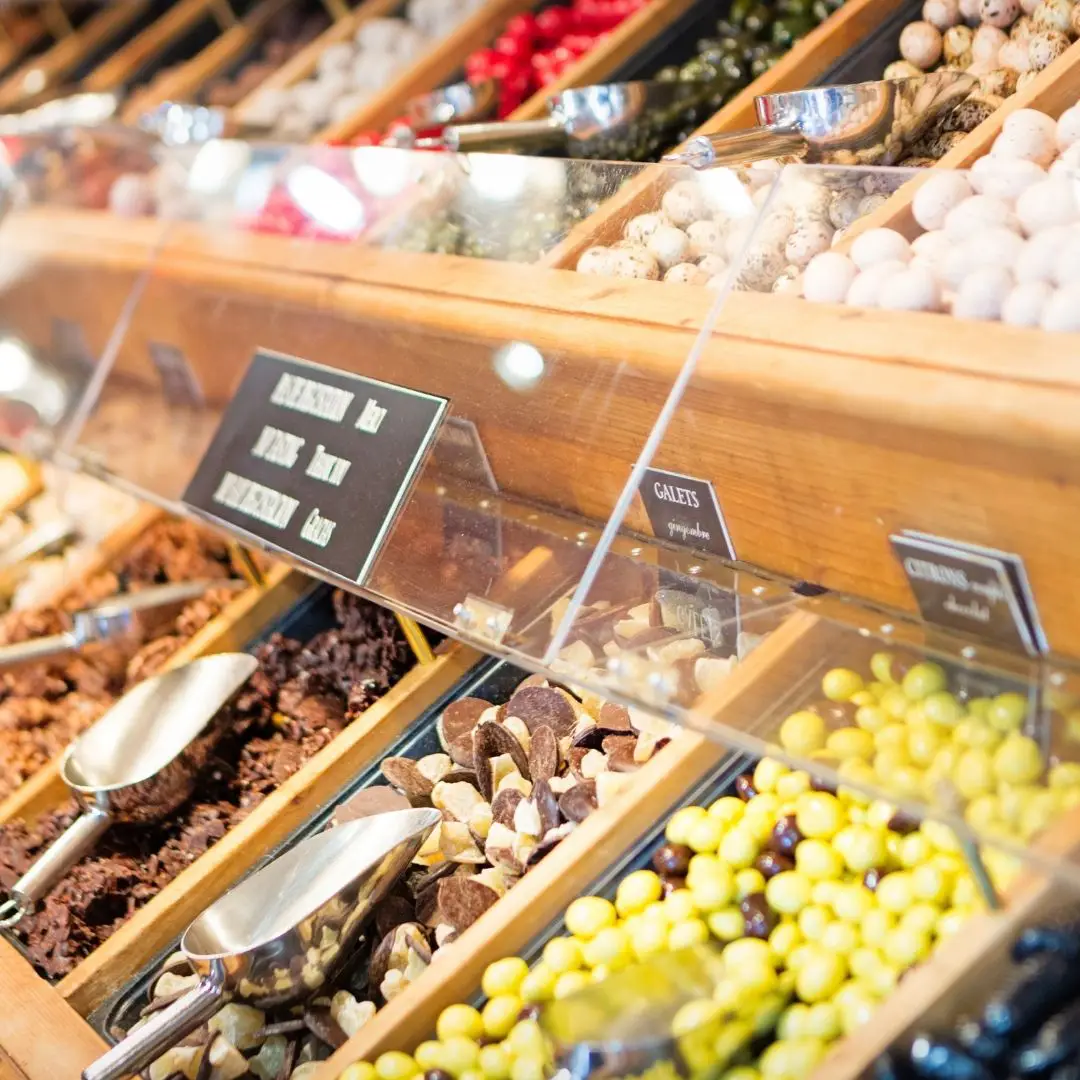 Closeup of bins of French candy with scoops in each bin.