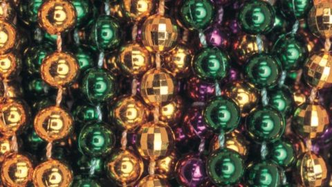Closeup of green, gold, and purple Mardi Gras beads.