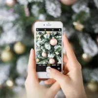 Closeup of a person taking a photo of a Christmas tree with an iPhone.