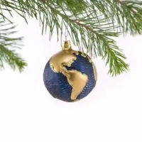 Closeup of a globe Christmas ornament hanging from an evergreen tree.