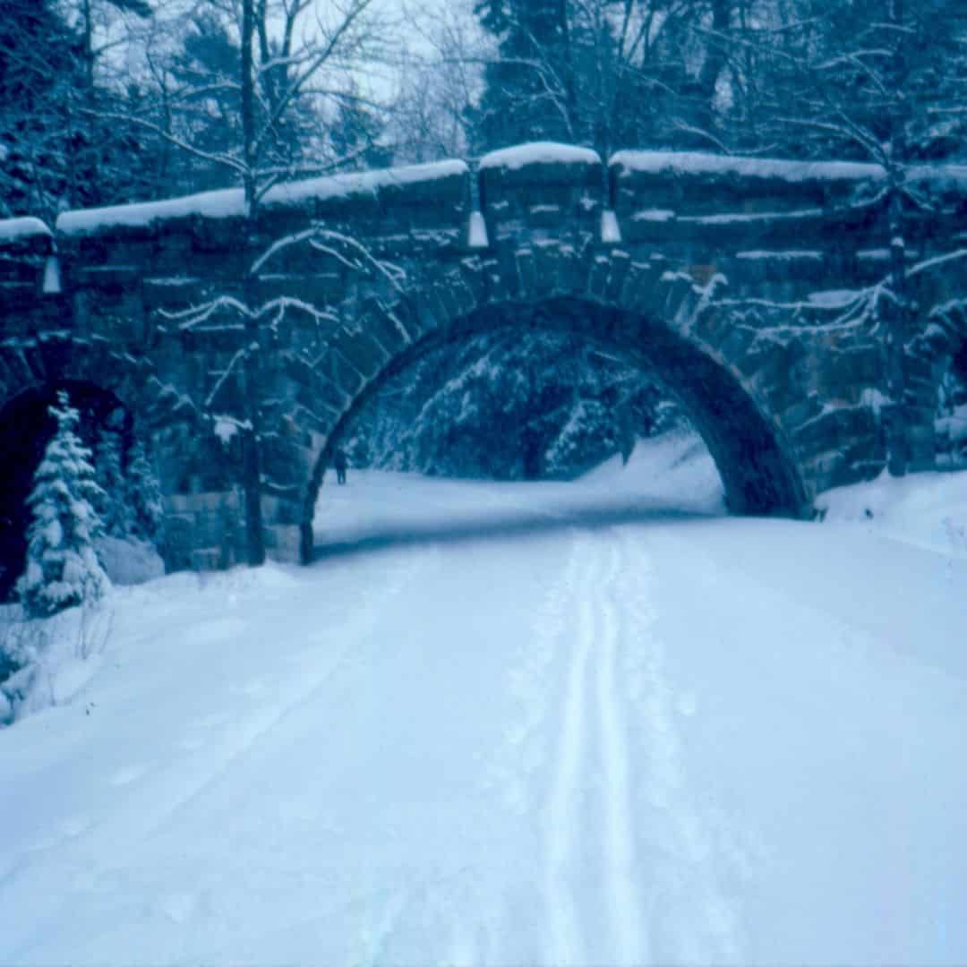 Photo of a stone bridge and carriage road in Acadia National Park covered in snow.
