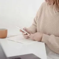 Closeup of a woman sitting at a desk, working on her smartphone.