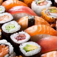 Closeup of a colorful platter of sushi and sashimi with lots of orange, salmon, and green colors.