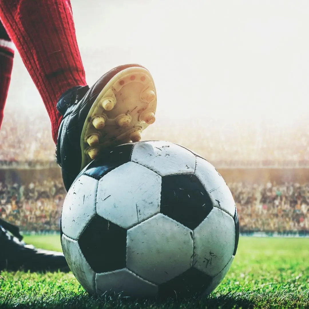 Closeup of a person wearing Soccer cleats with their foot on a Soccer ball.