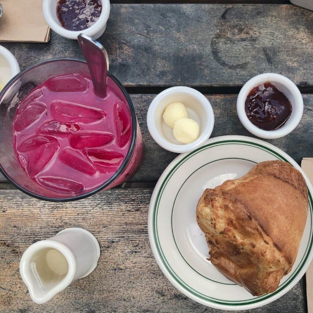 Flatlay photograph of a popover from Jordan Pond House and a glass of blueberry lemonade.