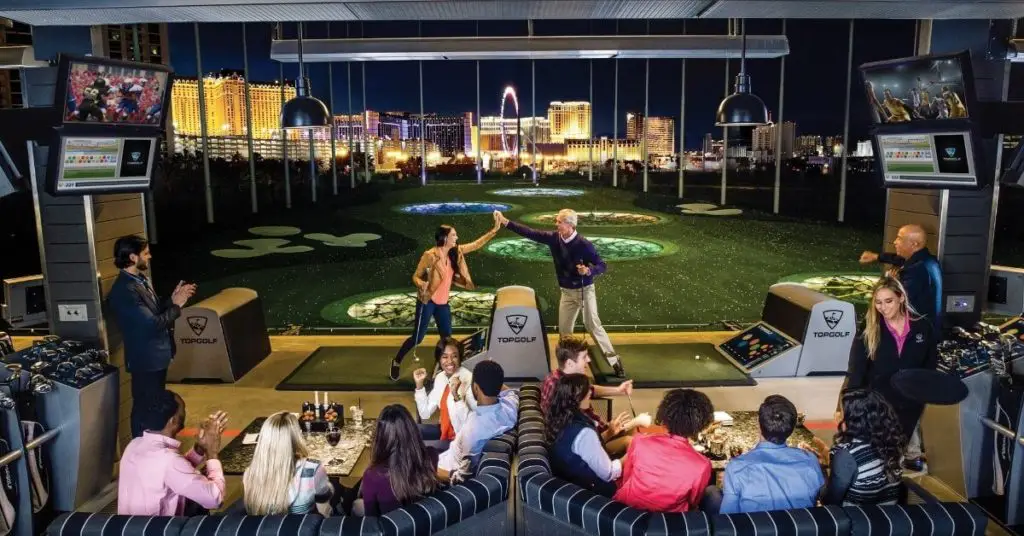 Photo of 2 groups of people hanging out at MGM TopGolf at night.