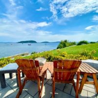 Closeup of 2 adirondack chairs overlooking Frenchman Bay in Bar Harbor, Maine.