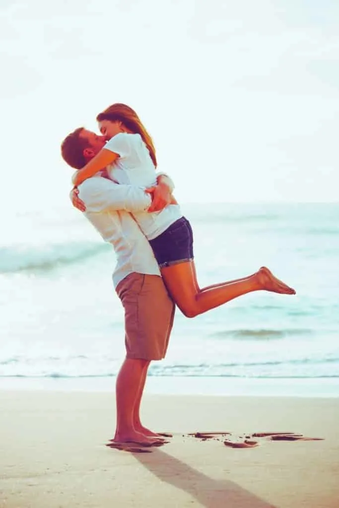 Photo of a man and woman holding hands while walking away from the camera on a beach. Text above the photo reads "This is the moment of sweet aloha. - Elvis"