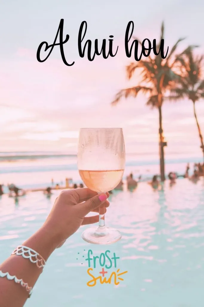 Photo of a hand holding a glass of rosé wine in front of a scene in Hawaii. Text above the photo reads "A hui hou," which is Hawaiian for "Until we meet again."