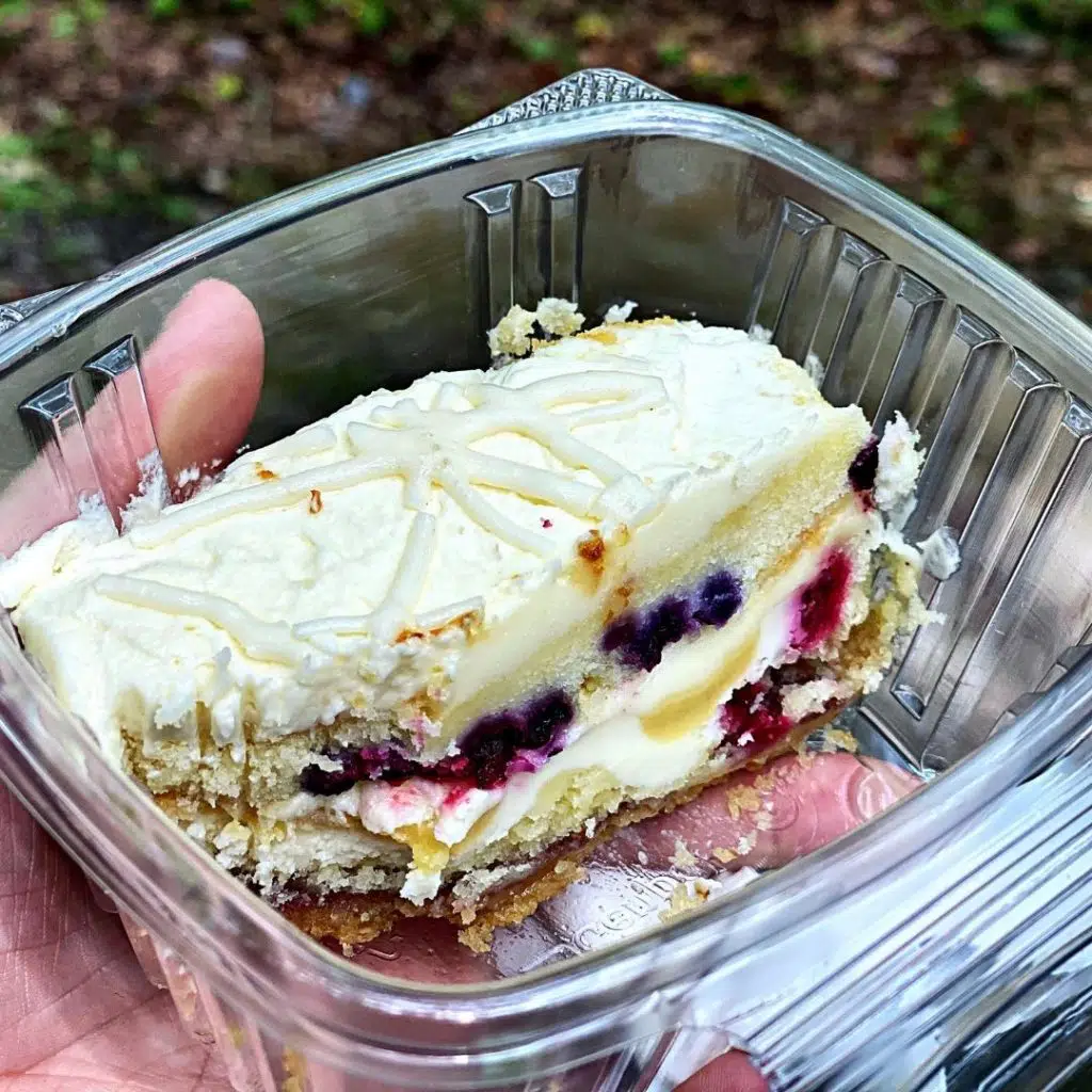 Closeup of a cake with layers of vanilla cake, frosting, and fresh berries.