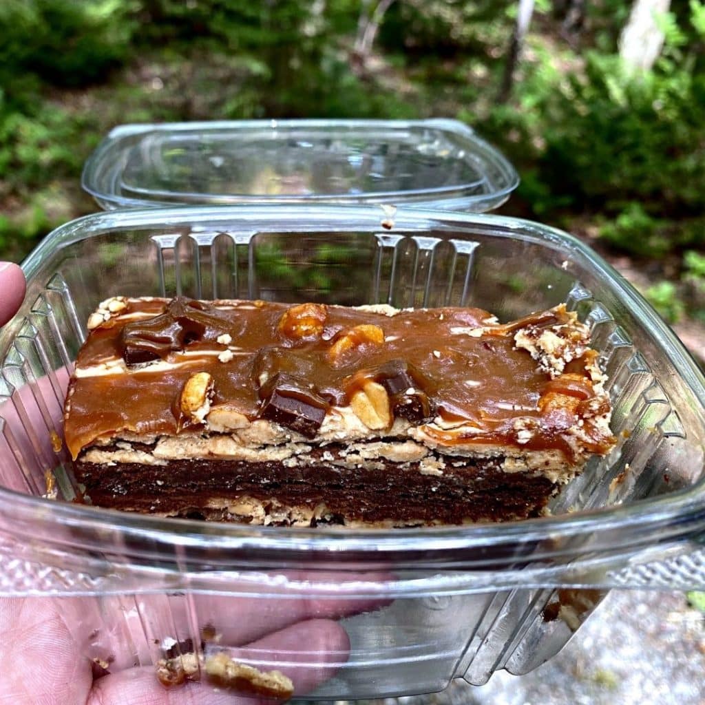 Closeup of a pastry with layers of chocolate, peanut butter, caramel, and other crunchy bits.