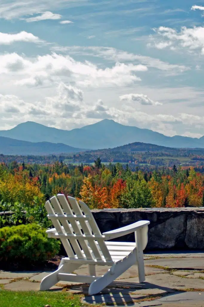 Photo of a white Adirondack chair overlooking a valley filled with Fall foliage from the Mountain View Grand Resort in New Hampshire.