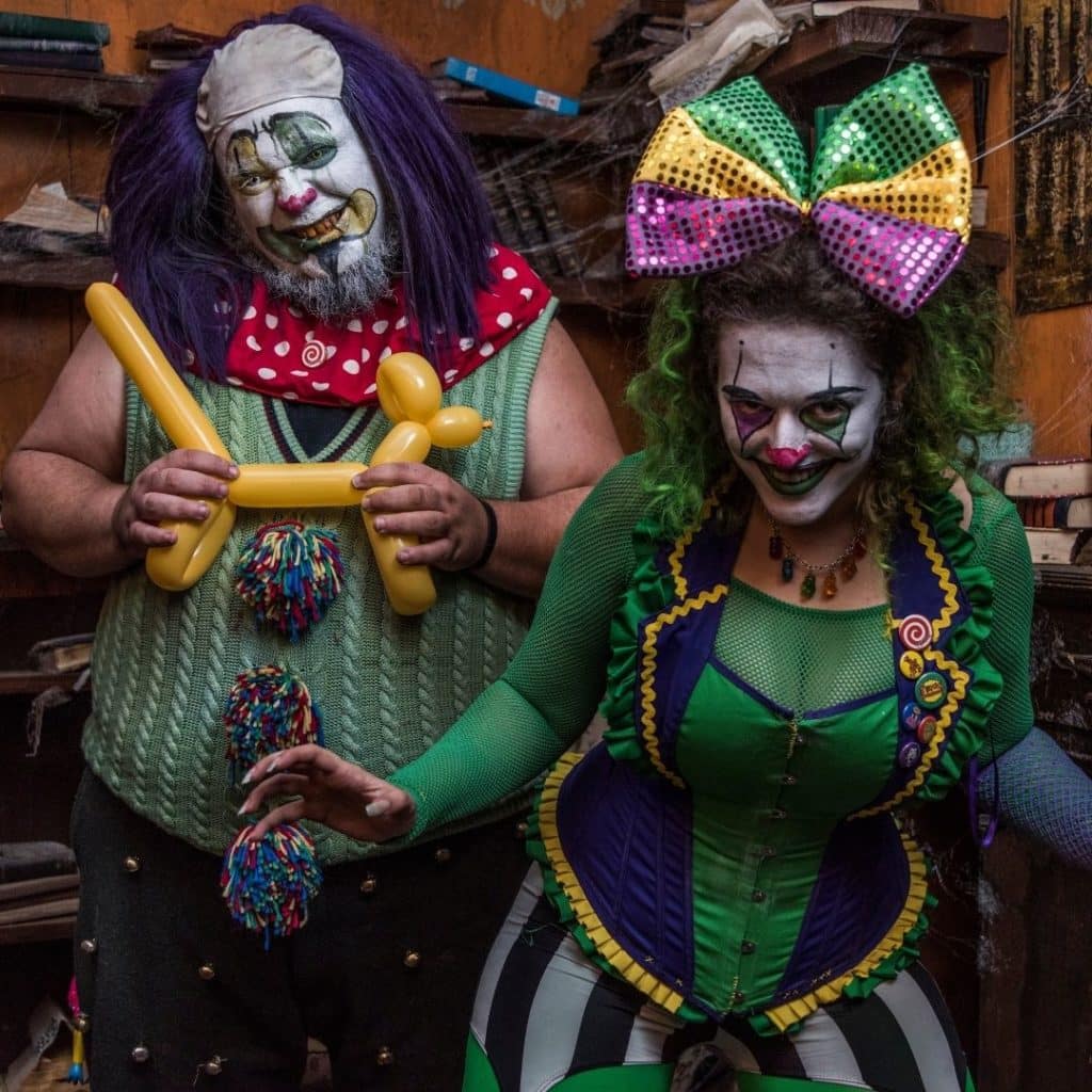 Photo of 2 creepy clowns dressed in green, yellow, and purple.