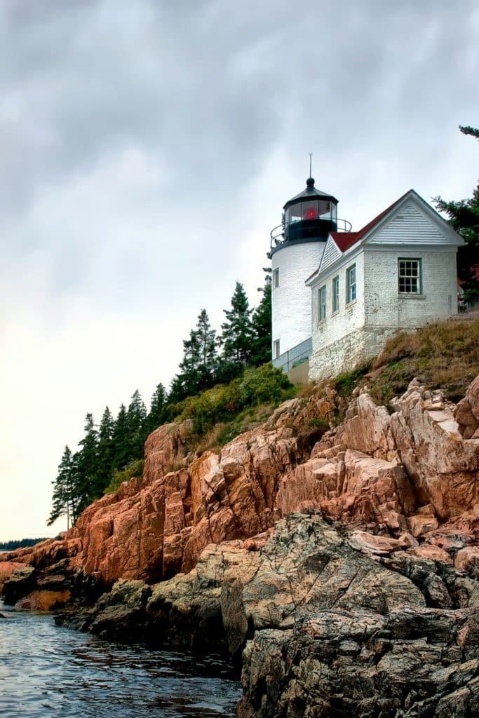 Photo of a bright white lighthouse perched on a rocky cliff.