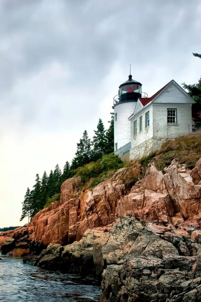 Photo of a bright white lighthouse perched on a rocky cliff.