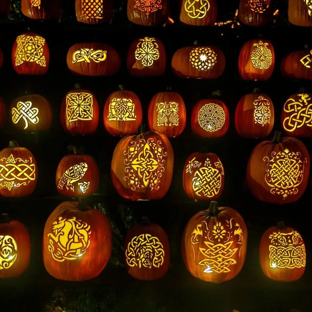 Photo of pumpkins with celtic knots carved into them, lit up from the inside.
