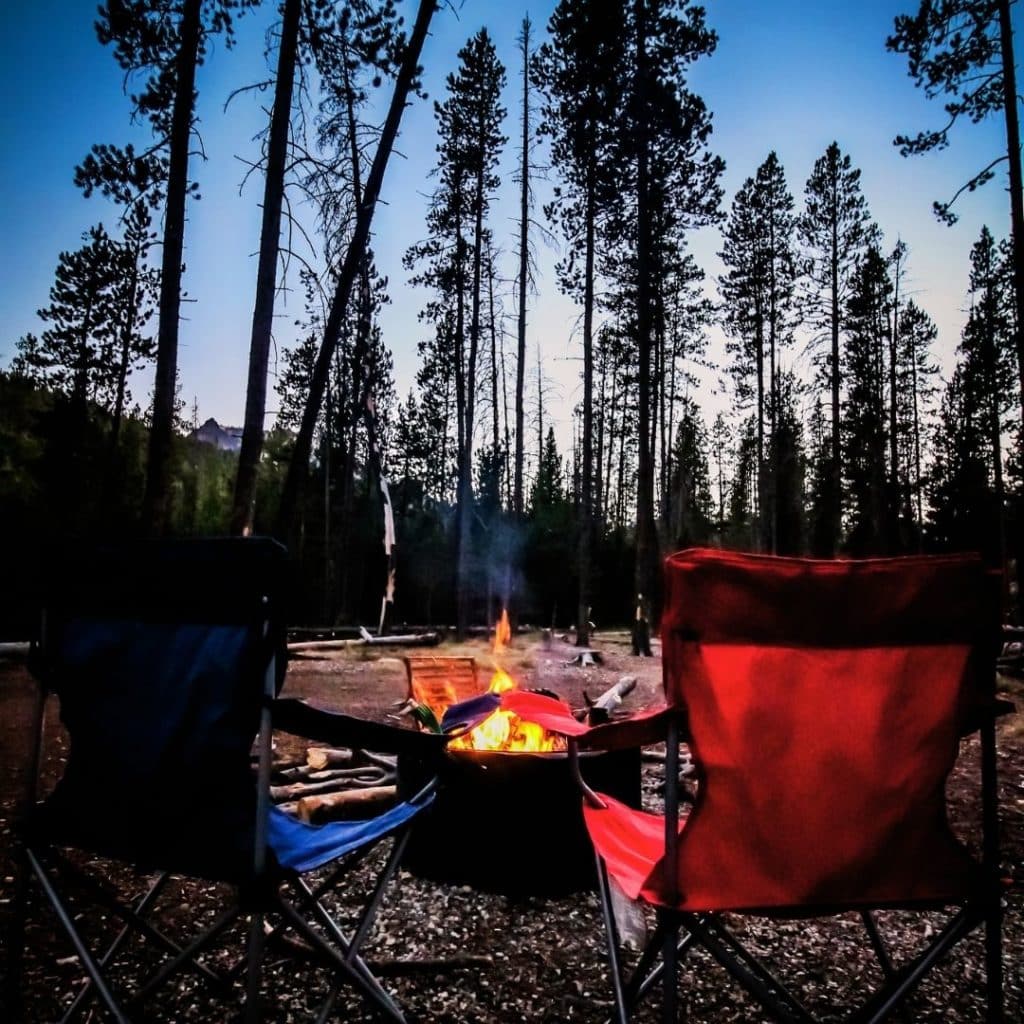 Photo of a bonfire with 2 camping chairs for kids in the foreground.