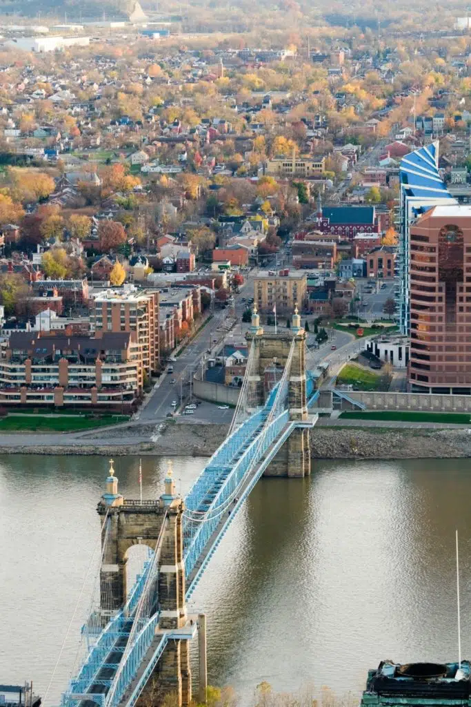 Aerial photo of Cincinnati with the Roebling bridge in the foreground and lots of Fall foliage dotting the landscape in the background.