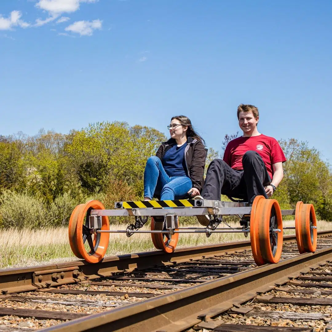Photo of a man and woman pedaling a rail bike.