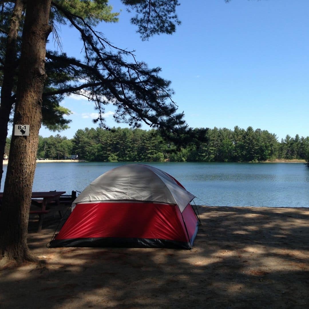 Photo of a camping tent set up on a lakeside beach.