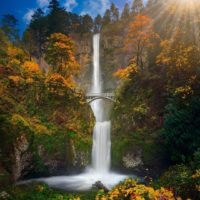 Photo of Multnomah Falls in Oregon with orange and yellow leaves on the trees.