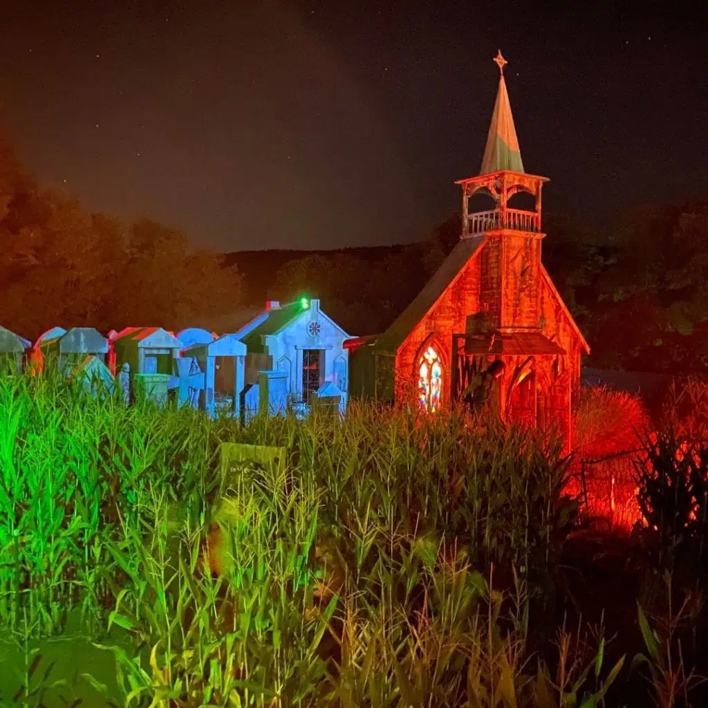 Photo of the outside of a haunted house setup next to a corn field at night.