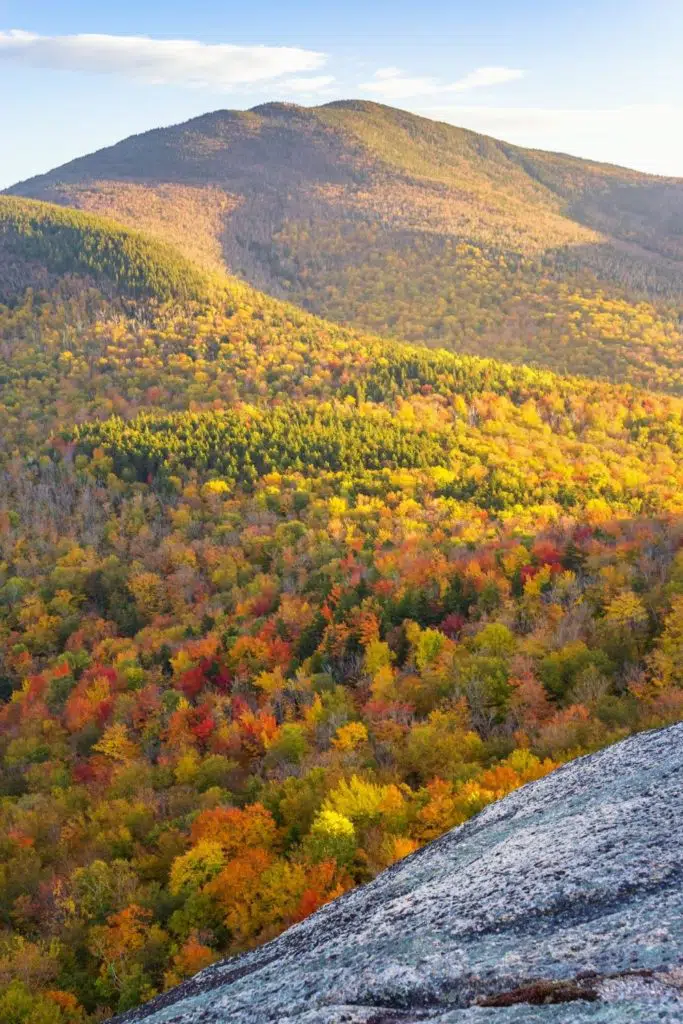 Photo of a valley full of Fall foliage from atop a mountain somewhere in New England.