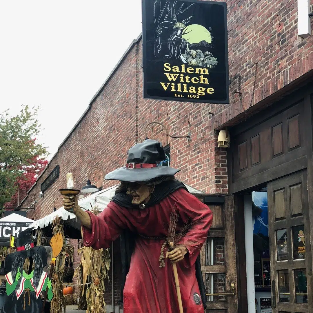 Photo of signage and decor outside the Salem Witch Village, including a large witch statue.