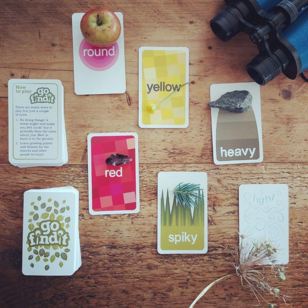 Flatlay photo of a scavenger hunt card game with found objects arranged nearby.